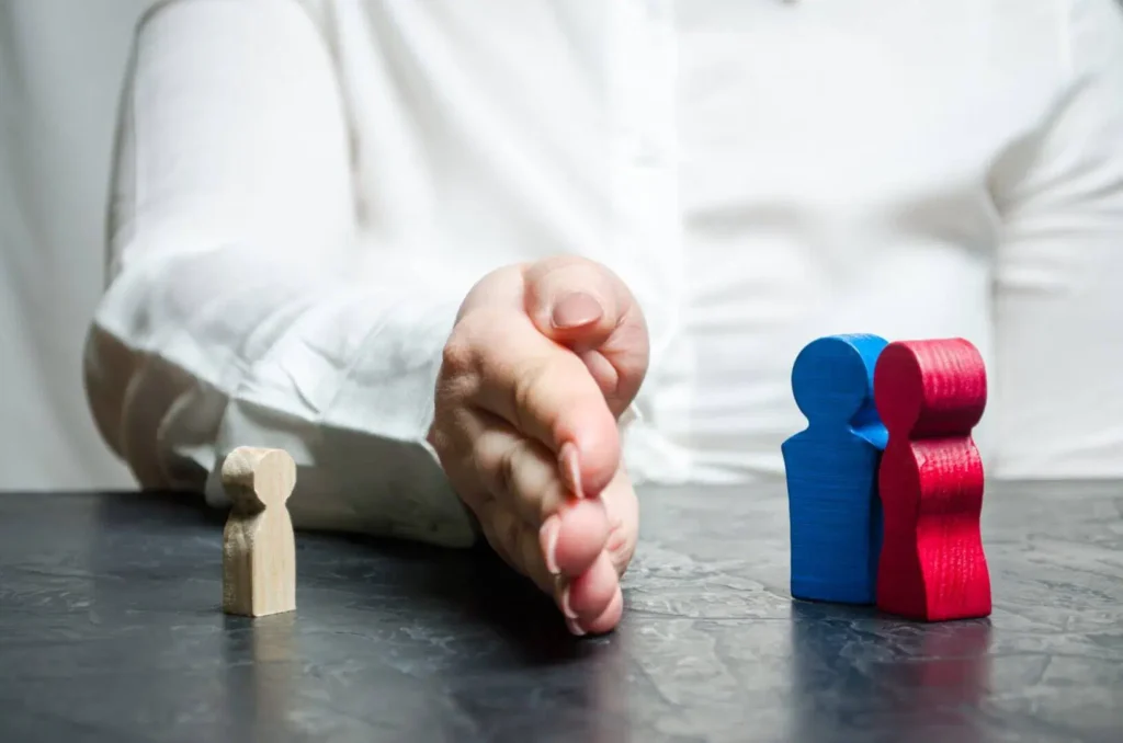 Hand separating wooden figures of parents and child, symbolizing family mediation, available at New Jersey Mediation.